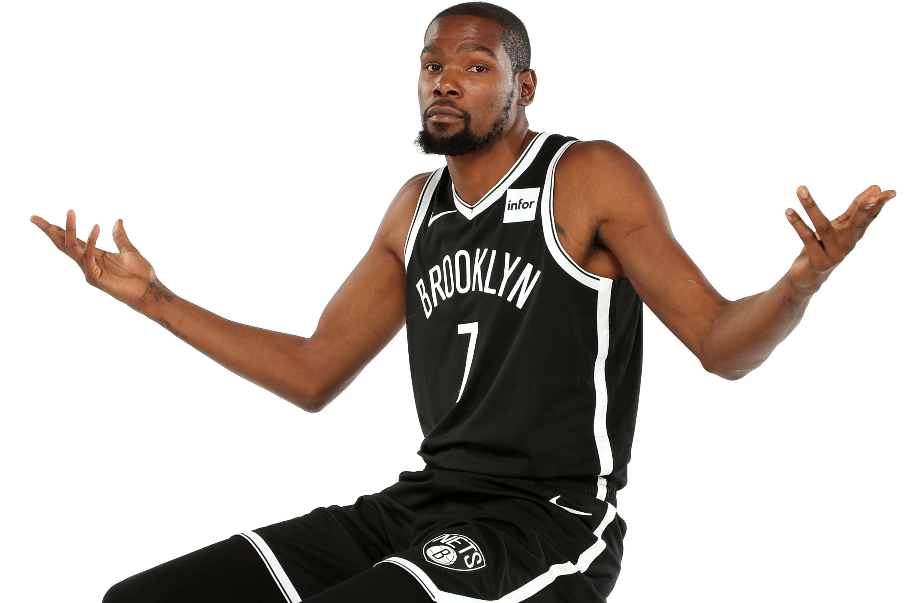Kevin Durant Nets Playful Shot Wallpaper — Basketball player Kevin Durant in Brooklyn Nets jersey sits with arms spread wide against white background.